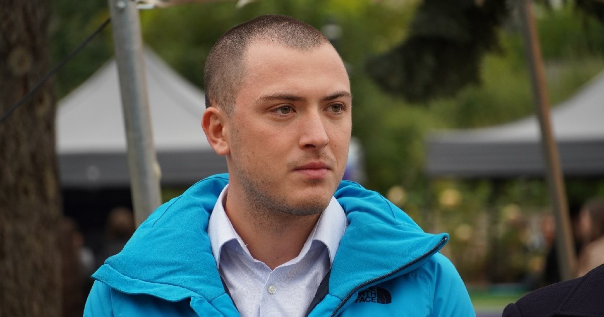 Un tânăr îmbrăcat în cămașă albă și geacă albastră