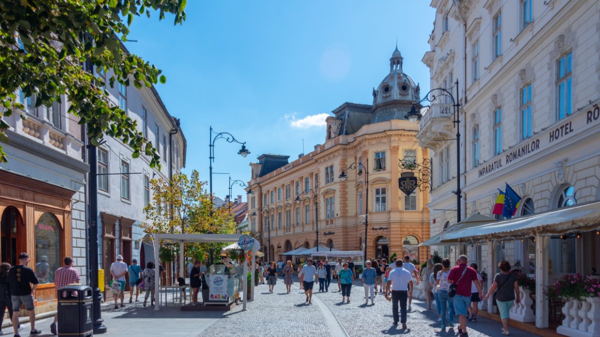 O stradă din centrul orașului Sibiu, oamenii se plimbă pe pietonală în timpul liber