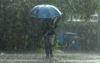 Imaginea surprinde o persoană care înaintează cu greu printr-o ploaie torențială pe stradă, protejându-se cu o umbrelă albastră sub un cer întunecat.