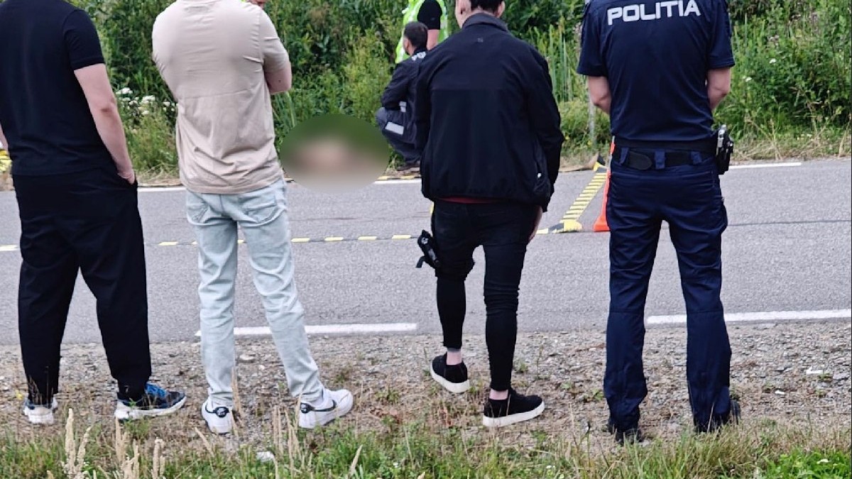 Trei tineri și un polițist, fotografiați cu spatele, în timp ce alți polițiști verifică un corp găsit pe marginea drumului