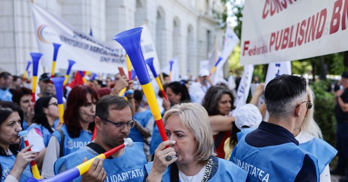 Protestatari îmbrăcați cu veste bleu suflă în vuvuzele în fața ministerului de finanțe din București, 10 iulie 2025