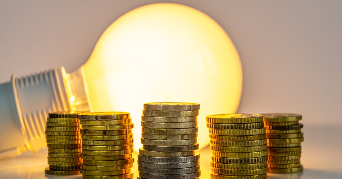 Mai multe teancuri de monede aurii puse pe o masă, iar în spatele lor este un bec aprins care dă o lumină galbenă
