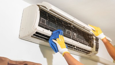 De ce trebuie să cureți periodic filtrele aparatului de aer condiționat- Un bărbat curăță interiorul unui aer condiționat