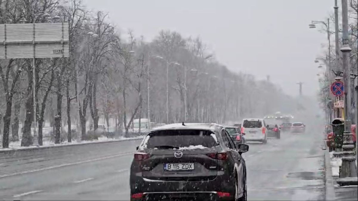 Mai multe mașini circulă pe Bulevardul Aviatorilor din București, pe timp de iarnă, iar pe străzi se vede ninsoare