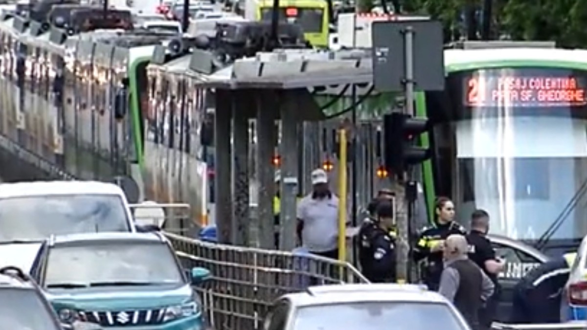 În centrul imaginii se observă un peron de tramvai unde sunt mai multe persoane, printre care și câțiva polițiști, în urma unui accident rutier.
