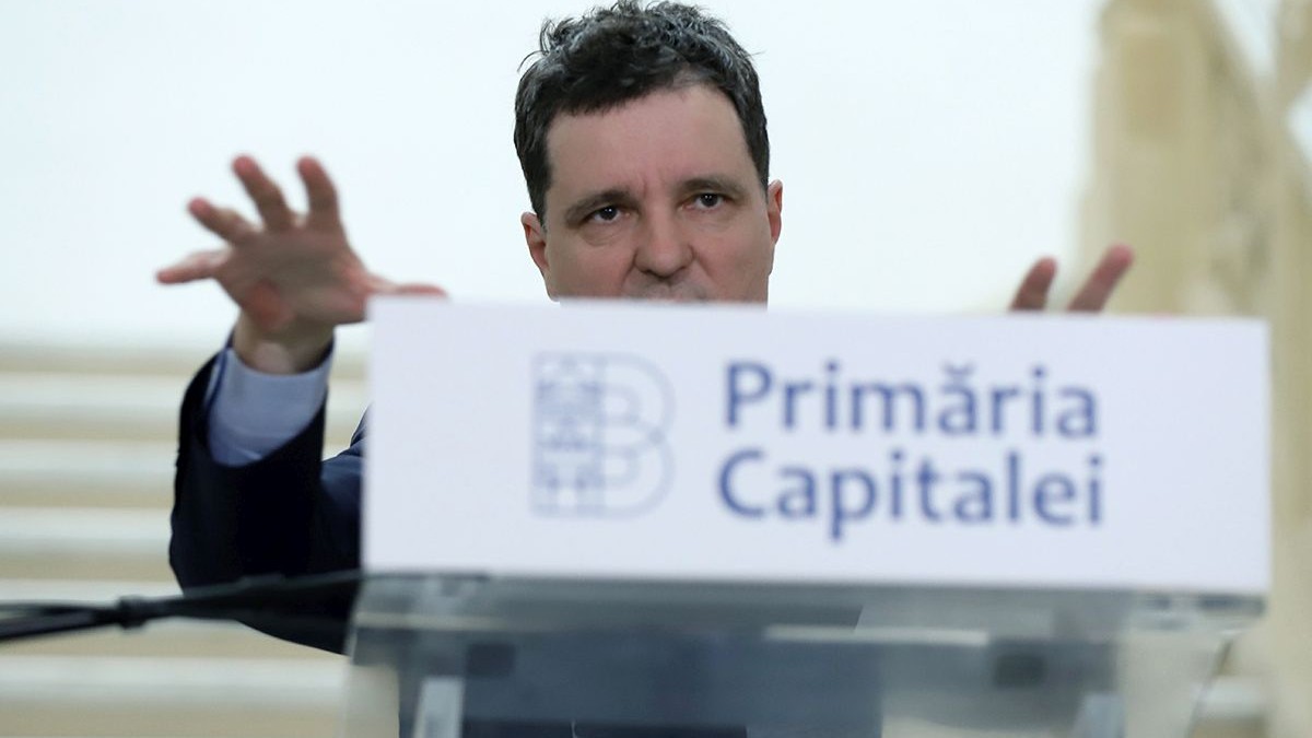 Nicușor Dan, candidat independent la alegerile prezidențiale, vorbește de la pupitrul Primăriei București și explică ceva, având mâinile cu degetele deschise