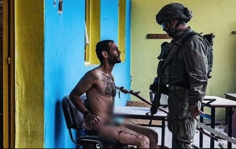 Soldat israelian care interoghează un palestinian dezbrăcat, legat la mâini și plin de sânge. Experți juridici: „Rele tratamente aplicate prizonierilor”