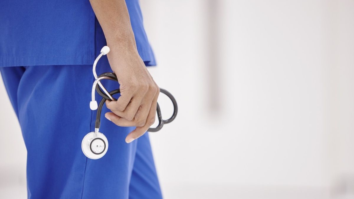 Un medic ține în mână în stetoscop, pe holul spitalului.