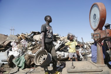 Un lucrător din Zimbabwe privește cântarul la un centru de fiare vechi din Hopley, Harare, pe 8 iulie 2022. Somajul de peste 90% din țară a împins mulți oameni în acest domeniu.