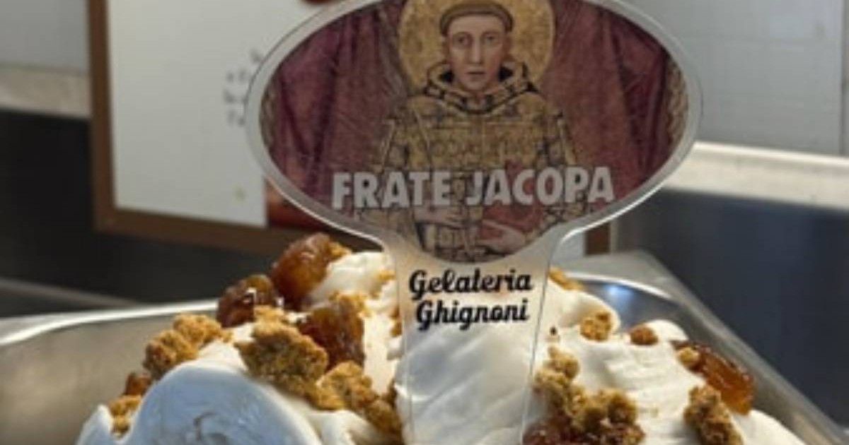 Tavă de gelaterie cu înghețată albă, decorată cu bucăți de biscuiți și topping brun. În mijloc apare un cartonaș cu Sfântul Francisc și numele „Frate Jacopa”.