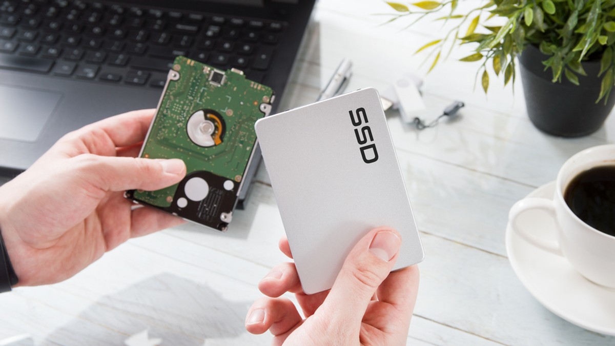 Memorii HDD şi SSD în oferta eMAG de Black Friday 2022 - Bărbat care ţine într-o mână un Hard Disk şi în cealaltă o memorie SSD