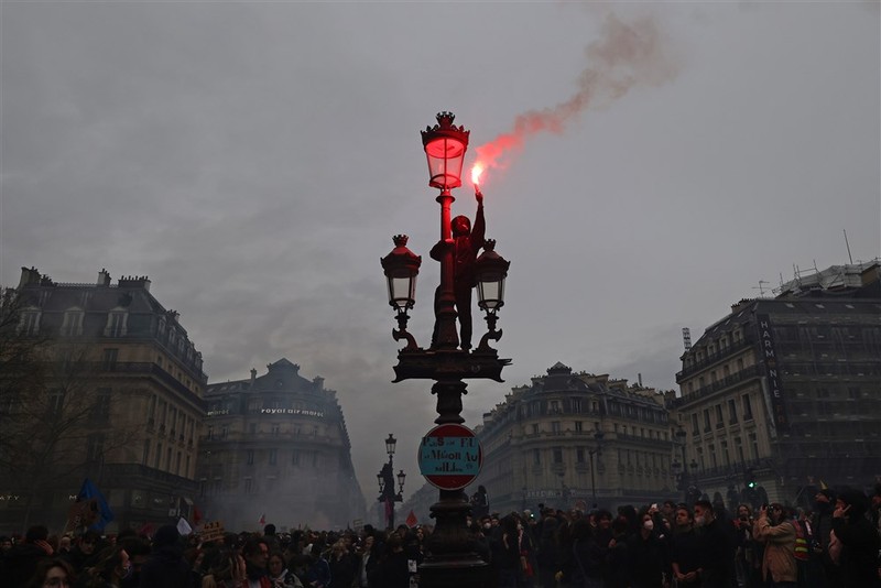 epa10539134 A protester lights a flair as thousands of people participate in a protest against the government's reform of the pension system in Paris, France, 23 March 2023. Protests continue in France after the prime minister announced on 16 March 2023 the use of Article 49 paragraph 3 (49.3) of the French Constitution to have the text on the controversial pension reform law - raising retirement age from 62 to 64 - be definitively adopted without a vote. EPA-EFE/MOHAMMED BADRA