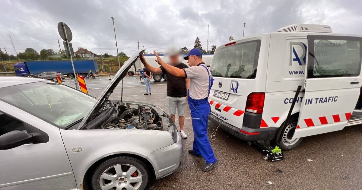 Control tehnic rutier realizat de Registrul Auto Român (RAR). Un inspector RAR, îmbrăcat în salopetă albastră discută cu un șofer în fața unui autoturism argintiu cu capota ridicată.