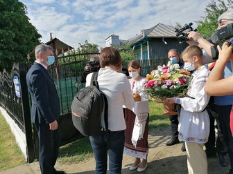 Doi tineri, îmbrăcați în straie populare, sunt aduși pentru a o întâmpina pe Ioana Mihăilă cu pâine și sare