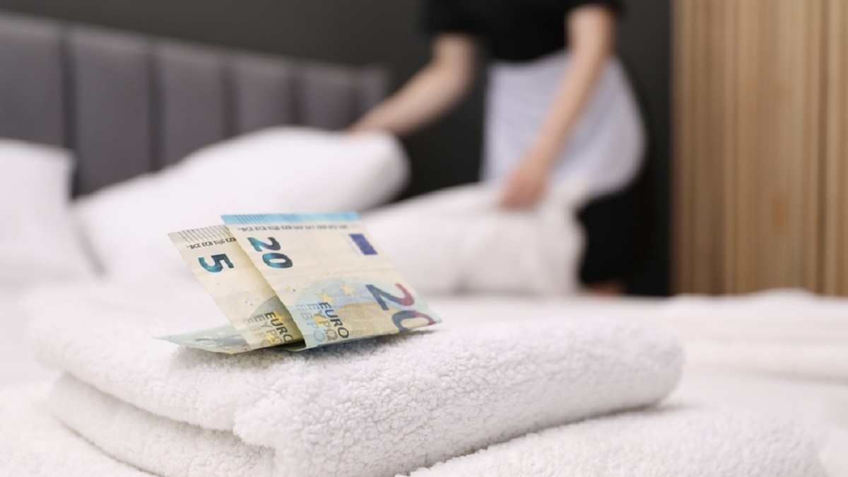 Ce bacşiş ar trebui să dai la hotel - Imagine cu suma de 25 de euro asezaţi pe un set de prosoape de pe patul dintr-o cameră de hotel, sugerând bacşişul lăsat unei cameriste