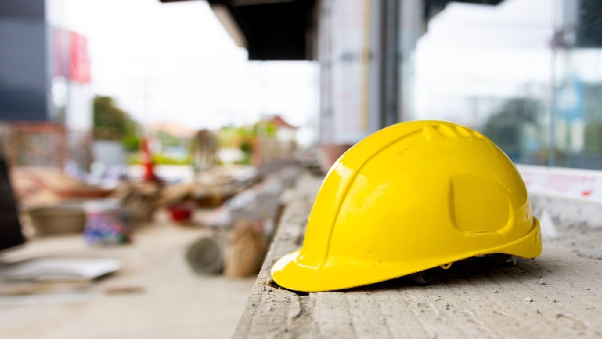Cască de protecție galbenă atârnată pe șantier, reprezentând ingineria, munca calificată și măsurile de siguranță industrială