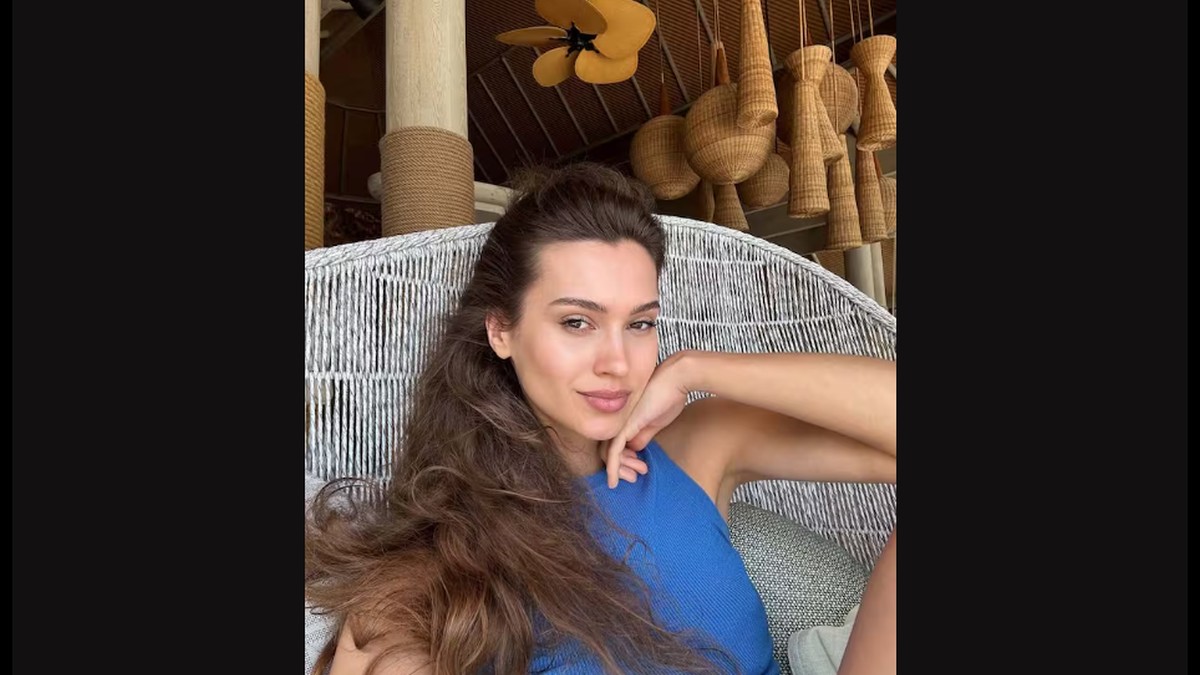 Kseniya Aleksandrova, fostă miss Rusia, zâmbește stând într-un fotoliu și îmbrăcată cu o rochie albastră, iulie 2024