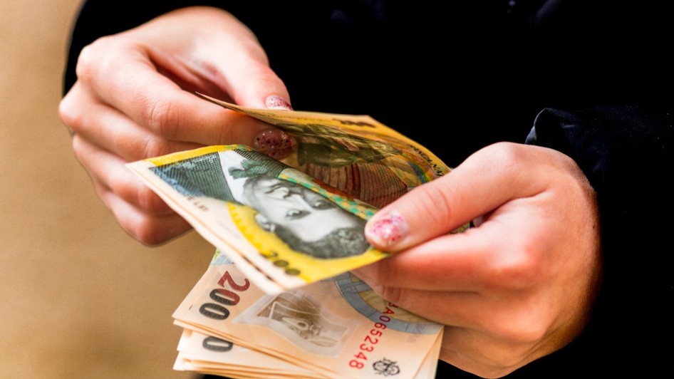 O tânără care numără mai multe bancnote de 200 de lei 