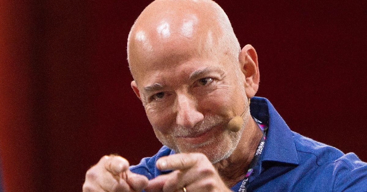 Jeff Bezos îmbrăcat cu o cămașă albastră și gesticulează