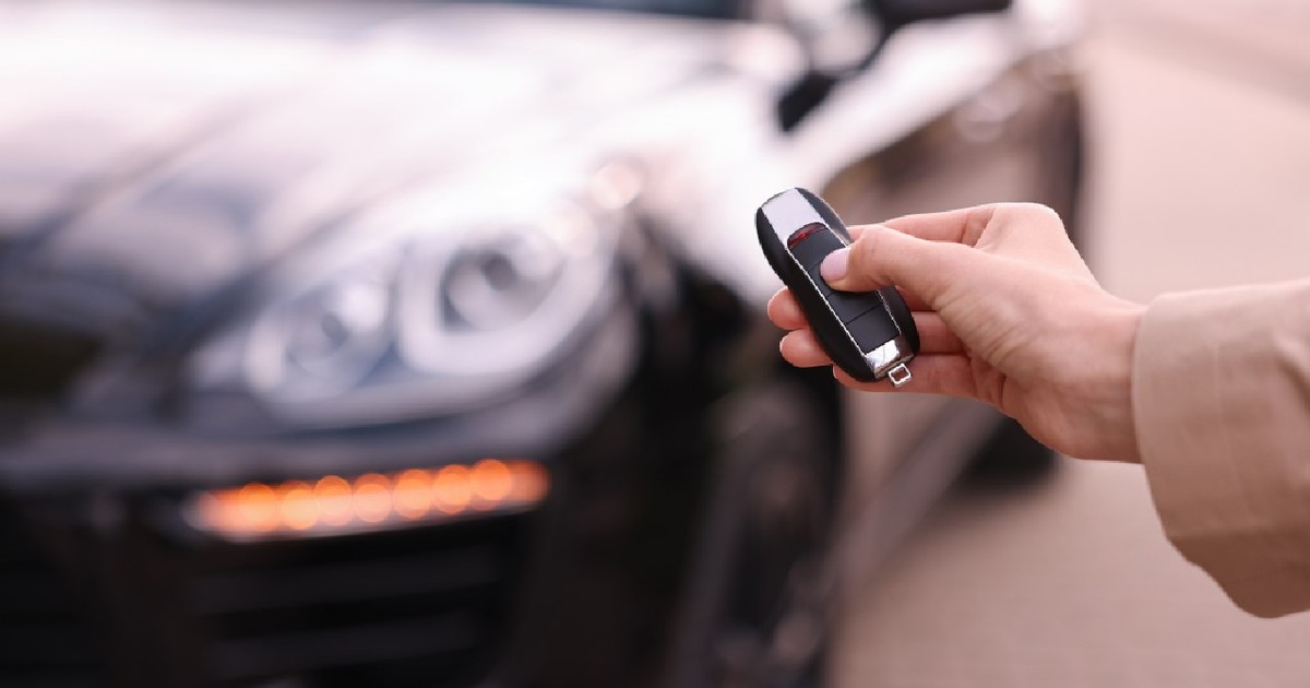 O femeie ține cheia mașinii lângă vehiculul său în aer liber