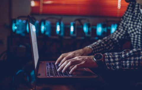 IT-ist lucreaza la laptop intuneric