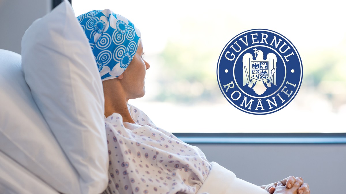 in poza se observa o femeie care sta pe un pat de spital langa geam. ea poarta o boneta albastra pe cap si un halat alb de spital cu floricele