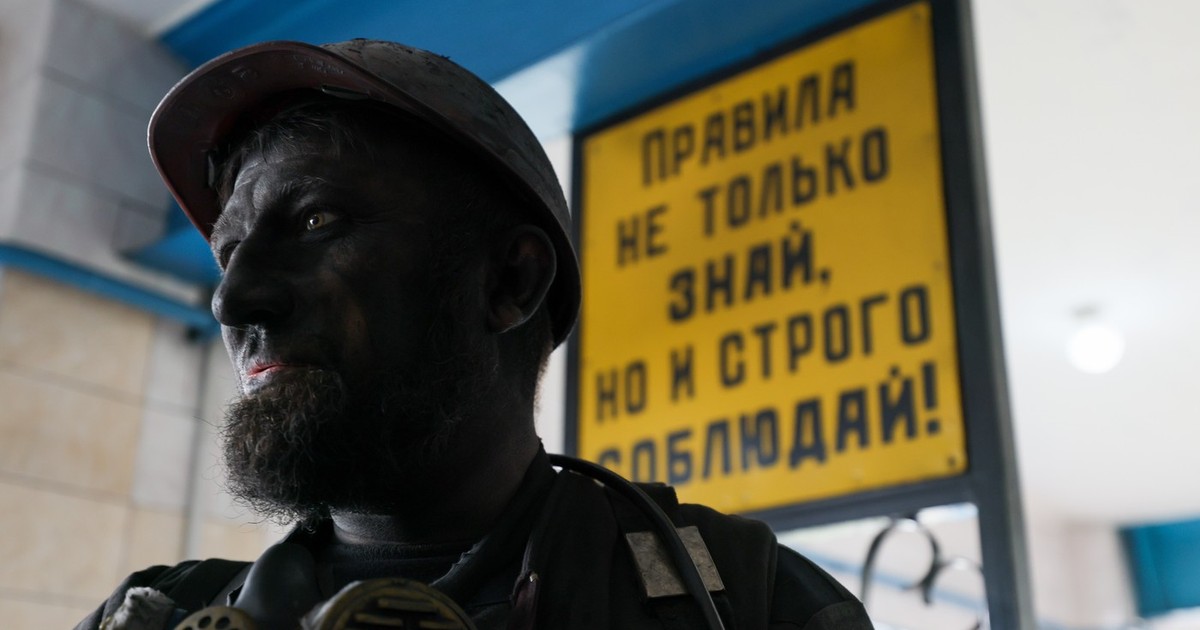 Un miner cu fata murdara de praf de carbune si casca pe cap este văzut la poarta principală a minei de cărbune Dolzhanskaya-Kapitalnaya, Rusia