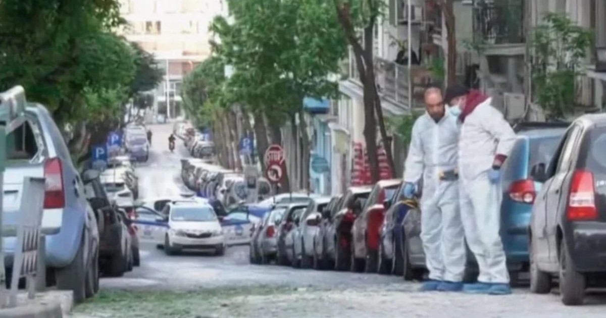 doii polițiști în combinezoane albe, pe o stradă cu mașini parcate de o parte și de alta, fac cercetarea la locul exploziei