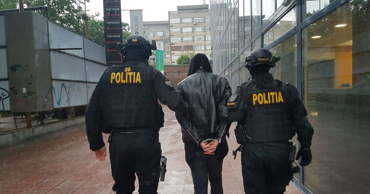 Doi polițiști escortează un bărbat acuzat de tâlhărie