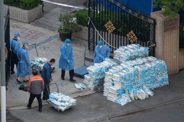 Angajați ai statului chinez organizează sacii cu orez ce vor fi distribuiți populației din Shanghai, pe 14 mai 2022. | Foto: Profimedia