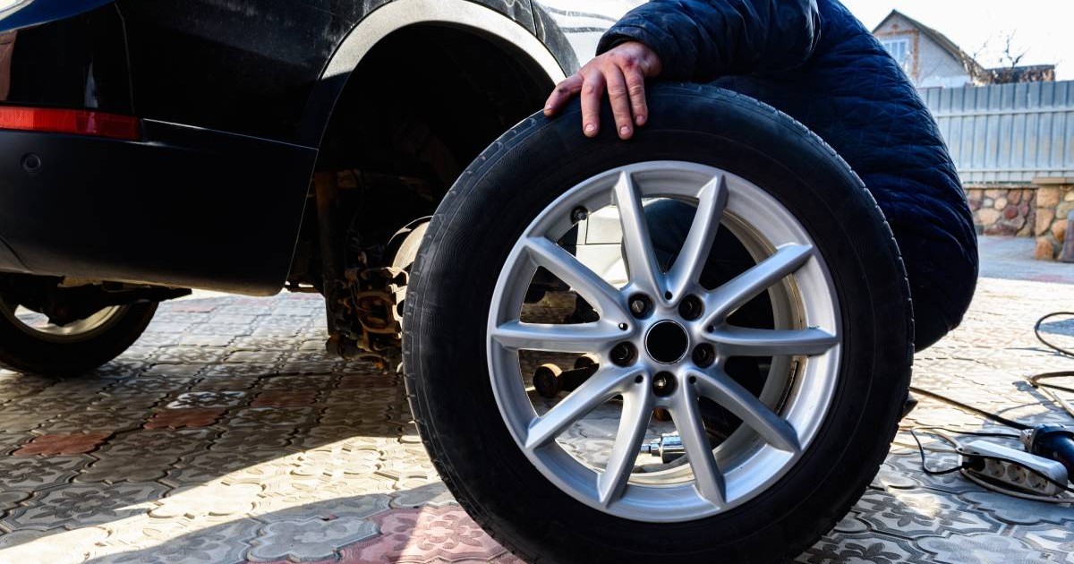 Schimbarea roților și anvelopelor pentru o mașină. Un om care desface și scoate roțile din curte