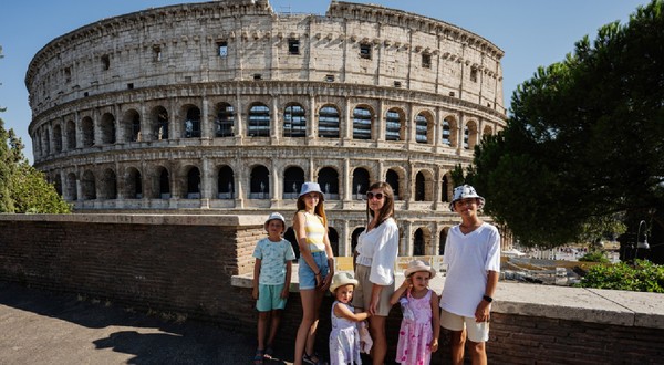 O mamă cu cinci copii pozează având Colosseumul ca fundal, în centrul istoric al orașului Roma, Italia.