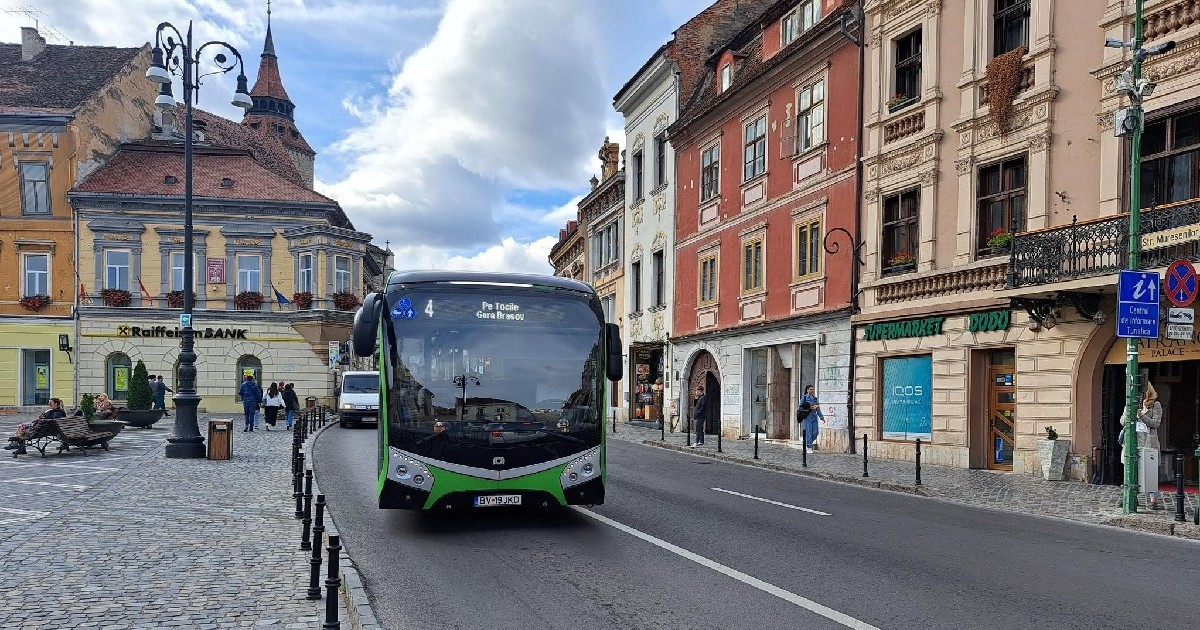 Un autobuz verde circulă pe o stradă din Brașov