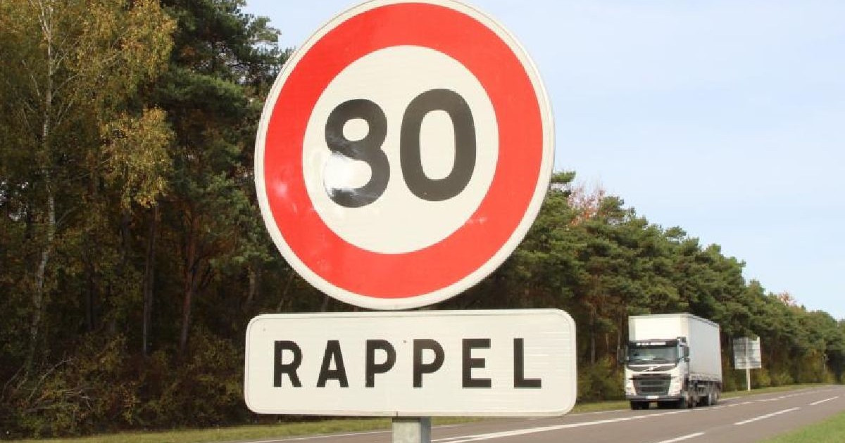 Fotografie cu un indicator de limită de viteză „80 km/h” pe o șosea, cu un camion alb care circulă în depărtare
