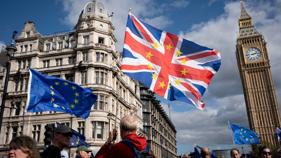 Manifestanți pro-europeni la Londra, fluturând steaguri ale Uniunii Europene și un steag combinat al Marii Britanii cu stelele UE, având turnul Big Ben pe fundal.   