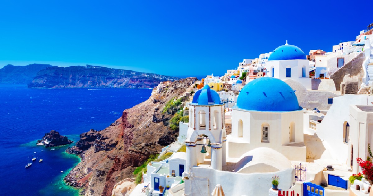 Orașul Oia pe insula Santorini, Grecia. Case și biserici tradiționale și faimoase cu cupole albastre cu vedere la Marea Egee