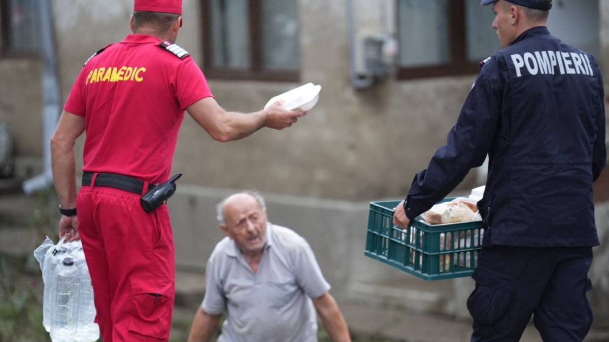 Pompierii din cadrul IGSU, în timp ce împart pâine și apă localnicilor din Broșteni, un bărbat trist primește de la aceștia două pachete și o sticlă de apă