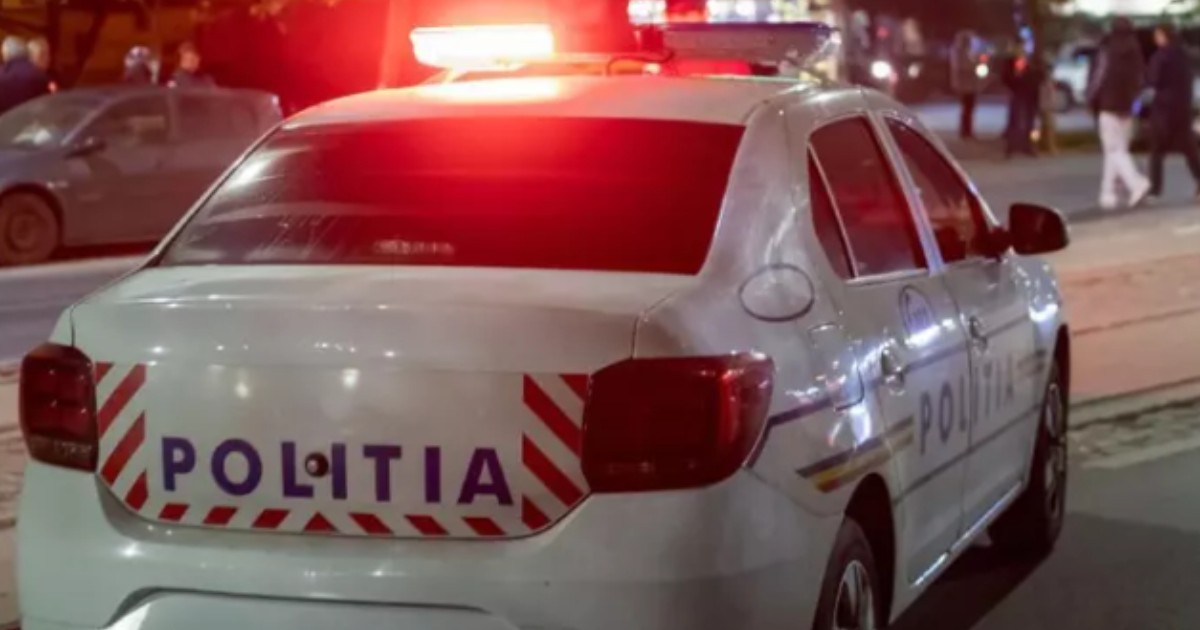 O mașină de poliție care are sirenele aprinse, noaptea.