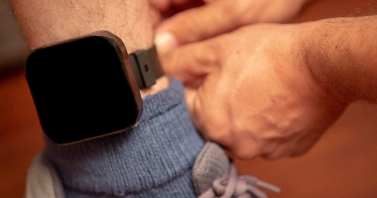 O brățară electronică neagră montată la glezna unui bărbat