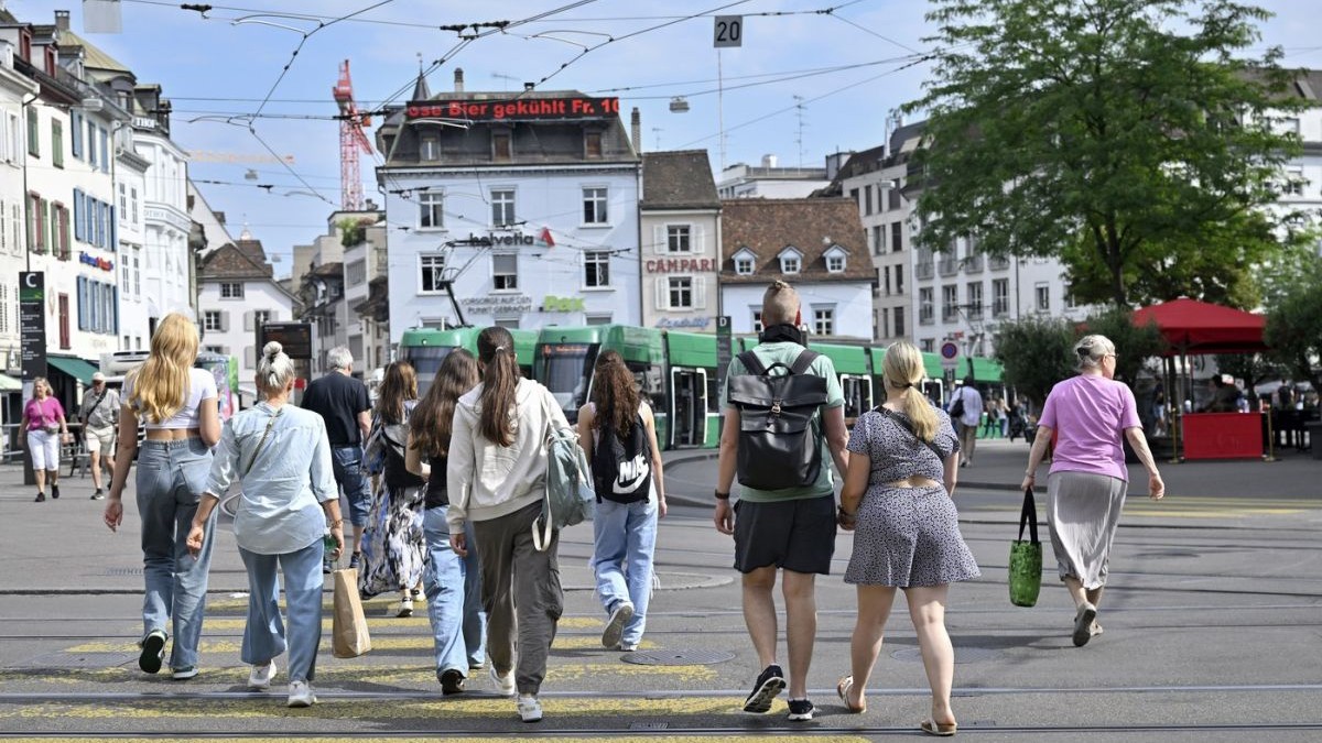 Mai multe persoane traversează o trecere de pietoni în Basel, Elveția.