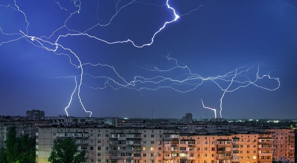 Furtună cu fulgere peste un oraș, cu blocuri în parte de jos a pozei, pe timp de noapte
