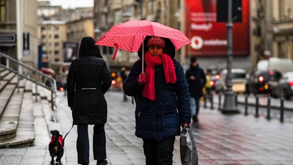 Femeie cu umbrelă plimbându-se într-o zi ploioasă pe bulevardul principal al orașului București, România