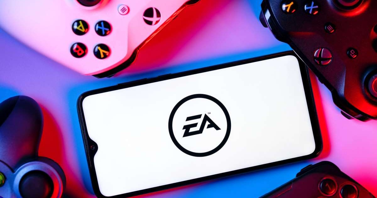 Logoul Electronic Arts, afișat pe ecranul unui smartphone așezat în mijlocul a mai multe controllere de PlayStation și Xbox.