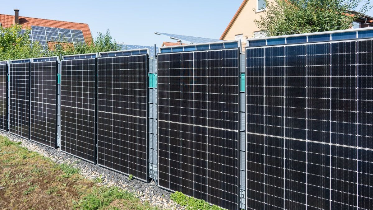 Gard solar modern, care produce energie, montat la o casă pe pământ
