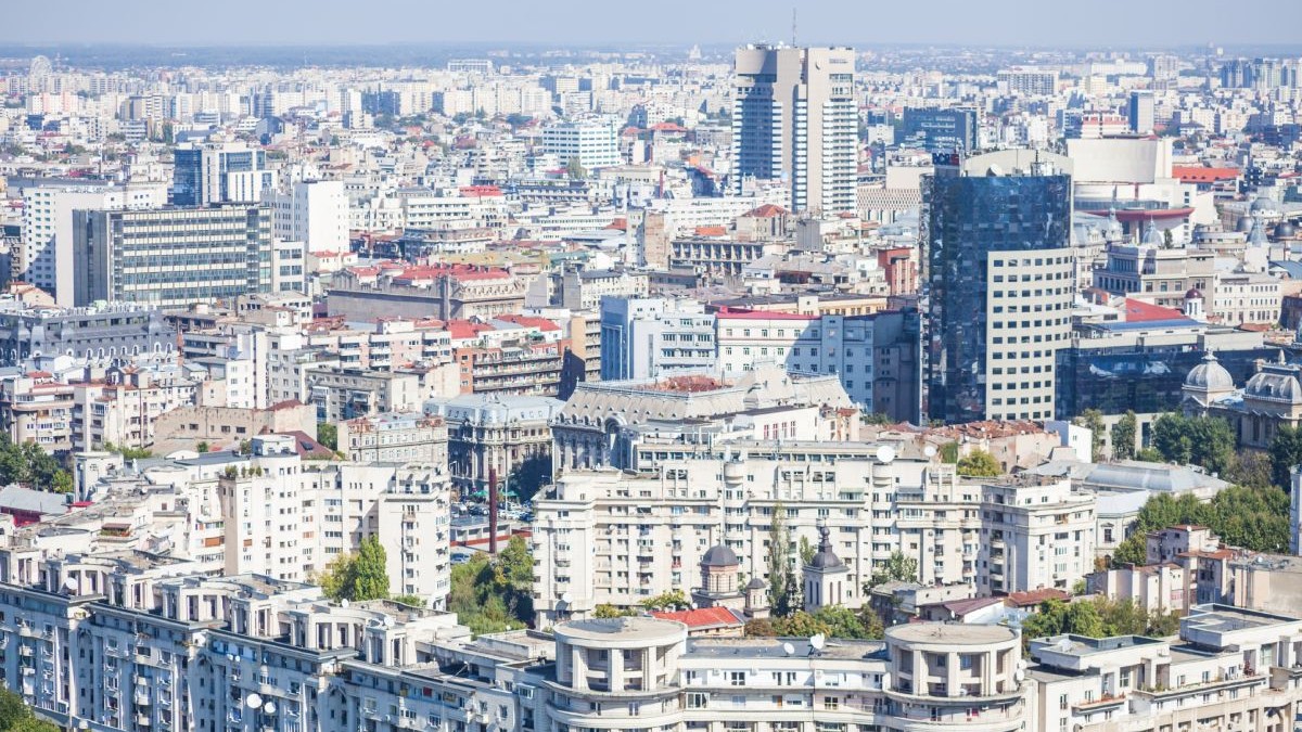 Imagine aeriană cu blocuri și clădiri din București, și cerul albastru pe fundal