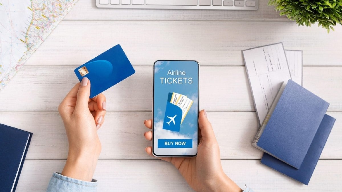 Femeie care își rezervă bilete de avion online, folosind un card bancar și un telefon mobil.