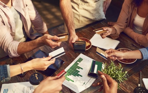 Mâini, carduri de credit, prieteni într-o cafenea, efectuând o plată sau o tranzacție bancară la un terminal POS.