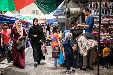 Într-un bazar aglomerat din Hebron, un cizmar repară clienților săi o pereche de pantofi