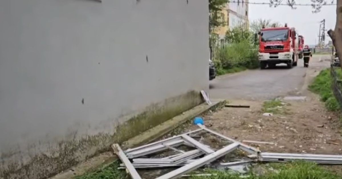 Explozie la un bloc, resturi pe jos, in fundal se vede un echipaj de intervenție al pompierilor