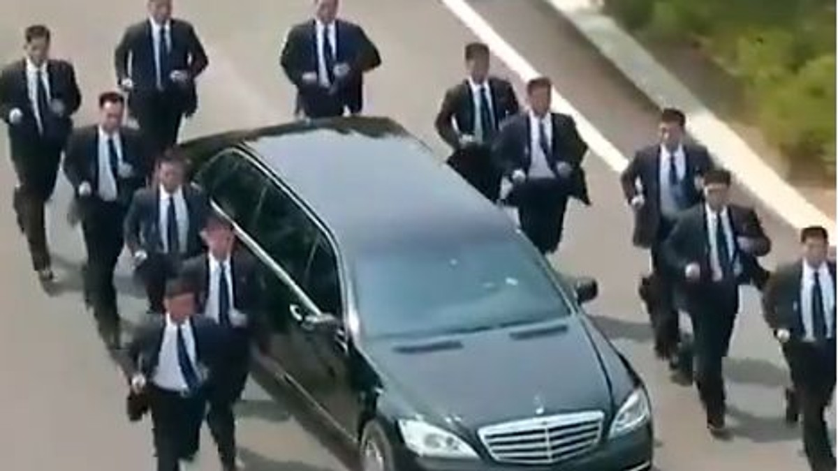 mulți bodyguarzi aleargă pe lângă mașina lui Kim Jong-un